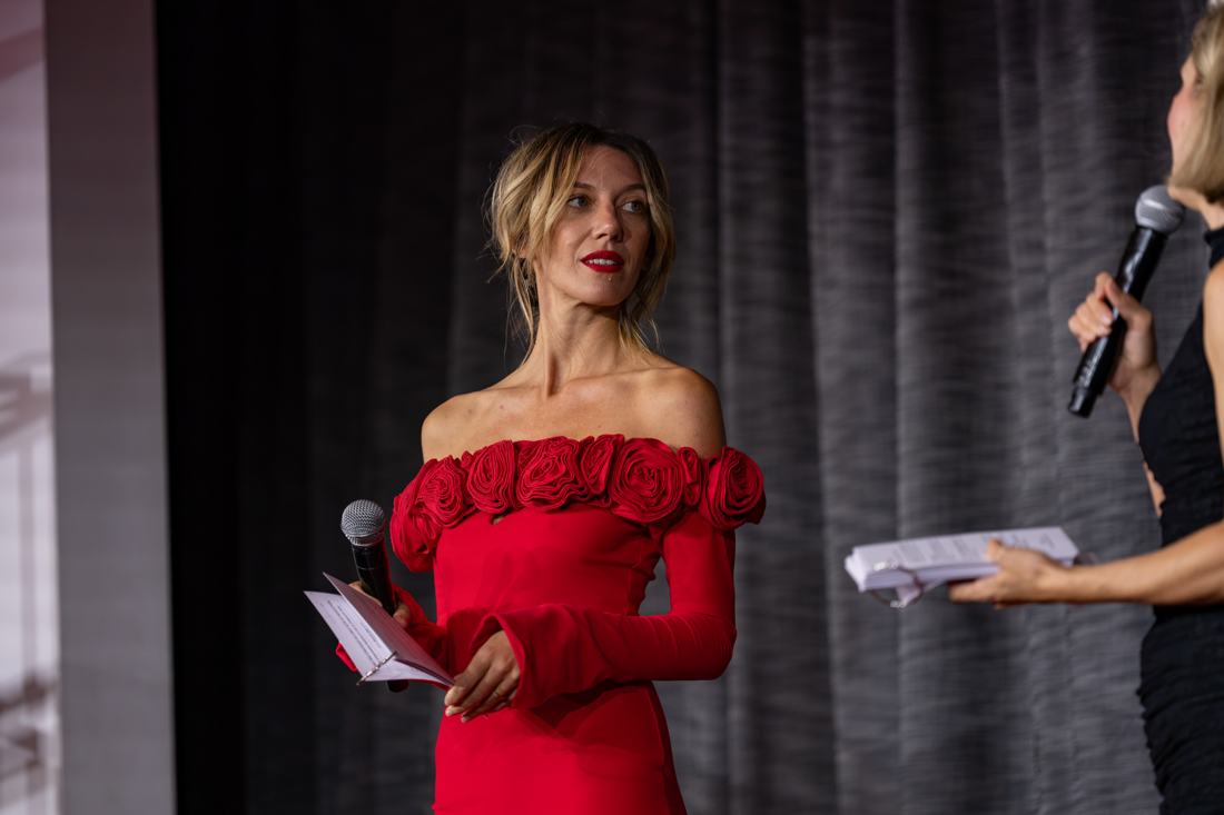 Salomé en robe rouge à roses, micro en main